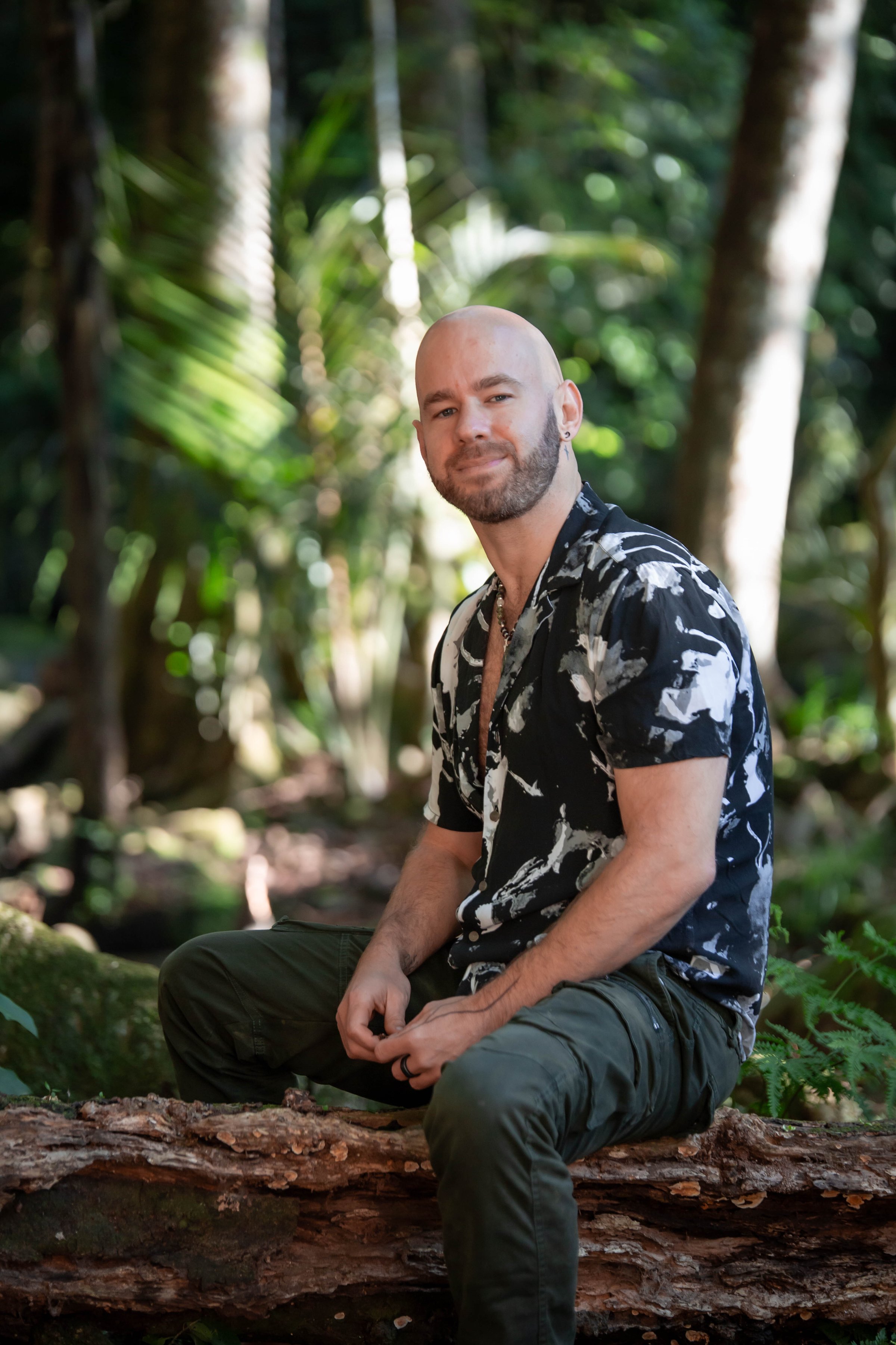 Gian Hart seated in native bush, looking directly at the camera with quiet presence